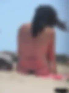 Brunette lady topless and in a black thong on the beach