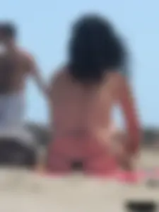 Brunette lady topless and in a black thong on the beach