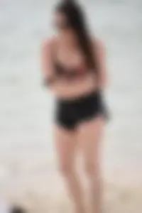 Brunette girl in black shorts and bikini top on the beach