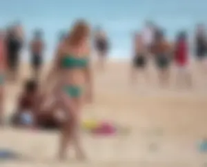 Sexy brunette in thong bikini and blonde friend in green bikini at the beach