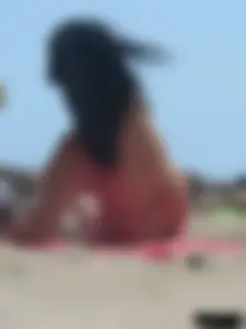 Brunette lady topless and in a black thong on the beach