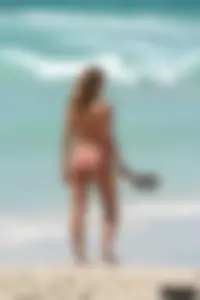 Topless girl in a tiny thong on the beach playing paddle ball