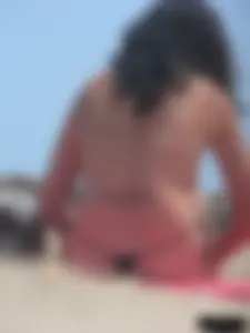Brunette lady topless and in a black thong on the beach