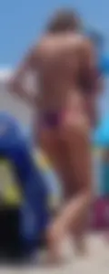 Sexy milf at the beach in a colorful semi thong bikini
