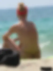 Topless skinny blonde lady in a g-string bikini at the beach