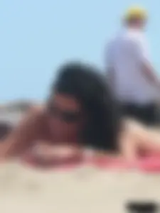 Brunette lady topless and in a black thong on the beach