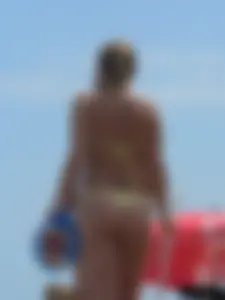 Sexy blonde on the beach in a yellow thong bikini
