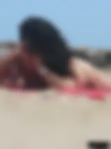Brunette lady topless and in a black thong on the beach