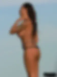 Topless tattooed lady on the beach with fake big tits