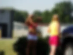 Group of cute girls at a car wash in bikinis and shorts