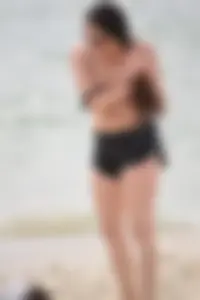Brunette girl in black shorts and bikini top on the beach