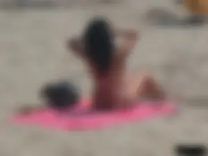 Brunette lady topless and in a black thong on the beach