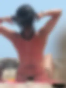 Brunette lady topless and in a black thong on the beach