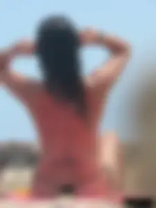 Brunette lady topless and in a black thong on the beach