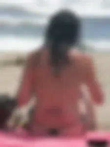 Brunette lady topless and in a black thong on the beach