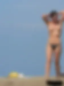 Sexy babe with a nice body topless and in a thong on the beach