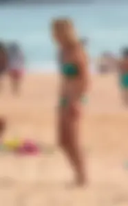 Sexy brunette in thong bikini and blonde friend in green bikini at the beach