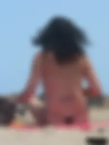 Brunette lady topless and in a black thong on the beach