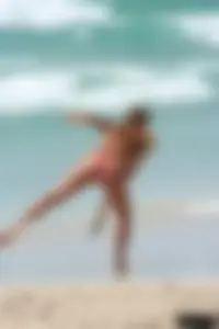 Topless girl in a tiny thong on the beach playing paddle ball