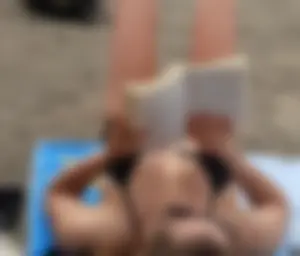 Lady in black bikini showing some pubes while laying out