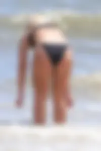 Beach blonde in the water in black bikini with a nice ass and small boobs