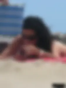 Brunette lady topless and in a black thong on the beach
