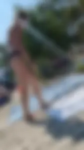 A pretty brown haired woman bending over with her nice ass in a black bikini on the beach. oc