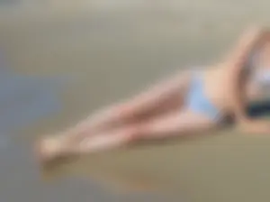 Skinny Girl in a Swimsuit Lying on Sand at the Shoreline