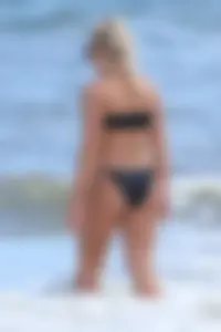 Beach blonde in the water in black bikini with a nice ass and small boobs