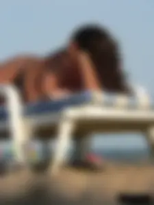 Topless tattooed lady on the beach with fake big tits