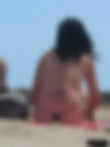 Brunette lady topless and in a black thong on the beach