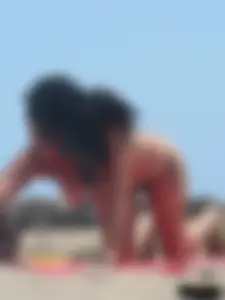 Brunette lady topless and in a black thong on the beach