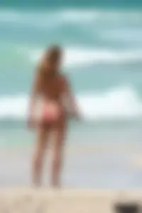 Topless girl in a tiny thong on the beach playing paddle ball