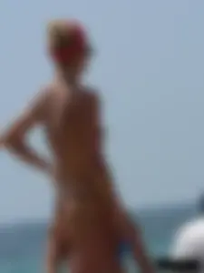 Topless skinny blonde lady in a g-string bikini at the beach