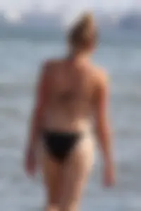 Strawberry blonde sexy mature girl walking the beach in black bikini