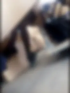 College girl's crossed legs in black pantyhose and a skirt seen from under desk in classroom