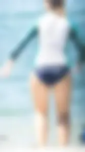 Girl in the water in a navy blue bikini bottom, shirt and hat with a nice ass