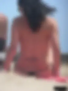 Brunette lady topless and in a black thong on the beach