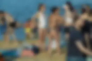 Girl in Sunglasses and a White One Piece Swimsuin Standing on Sand Beach Creepshots