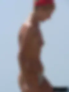 Topless skinny blonde lady in a g-string bikini at the beach