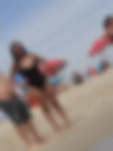Thick brunette with huge boobs on the beach in black swimsuit