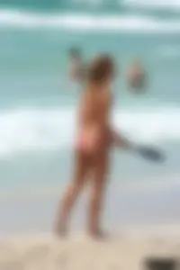 Topless girl in a tiny thong on the beach playing paddle ball