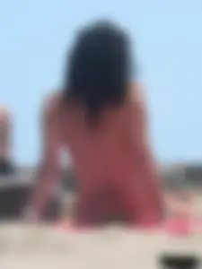 Brunette lady topless and in a black thong on the beach