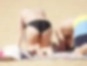 Sexy girl on the beach laying out and bending over in her bikini