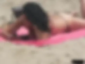 Brunette lady topless and in a black thong on the beach
