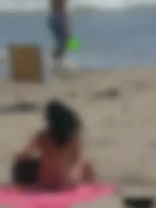 Brunette lady topless and in a black thong on the beach