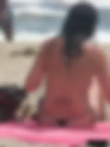 Brunette lady topless and in a black thong on the beach