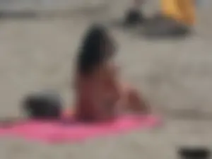 Brunette lady topless and in a black thong on the beach