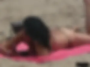 Brunette lady topless and in a black thong on the beach