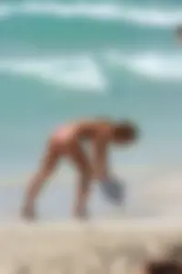 Topless girl in a tiny thong on the beach playing paddle ball